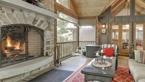 A cozy indoor patio with a stone fireplace, wicker furniture, and a view of the outdoors.