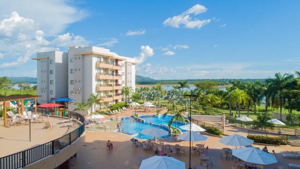 A hotel with a pool area, outdoor seating, and a view of the surrounding landscape. - MARINA FLAT - ACHEI FÉRIAS (Caldas Novas)