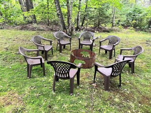 Relax in a serene garden setting with a fire pit at the center, surrounded by eight comfortable chairs.