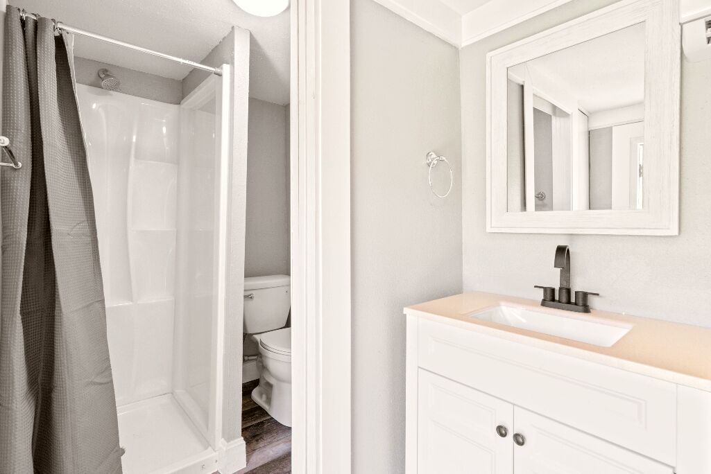 Une salle de bain équipée d’une douche, de toilettes, d’un lavabo et d’un miroir.