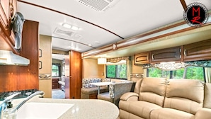 A well-equipped RV interior with a kitchenette, a dining area, and a comfortable seating area. - Fuel Your Passion for Epic Experiences and Outdoor Adventures at the Moto Ranch ATV! (Brooksville)