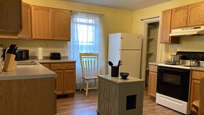 A compact kitchen with wooden cabinets, a refrigerator, a stove, and a microwave.
