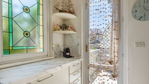 Una cucina con piano di lavoro in marmo, una macchina da caffè e un modellino di nave su uno scaffale.