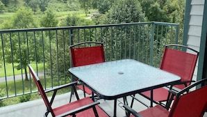 A balcony with a table and chairs, offering a view of a green landscape. - NO STAIRS!  Walk-in condo, Golf Course View, No pets allowed.  (Branson)