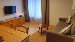 A compact living space with a flat-screen TV, wooden furniture, a small table, and a sofa. - 601 NEVADA 2 -estudi 2 pers- balco-Pas de la Casa -007647 (Pas de la Casa)
