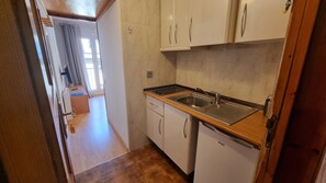 Een smalle keuken met een spoelbak, kastjes en een houten aanrecht.