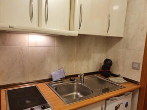 Une cuisine avec des meubles blancs, un évier en acier inoxydable, une cuisinière et un lave-vaisselle.