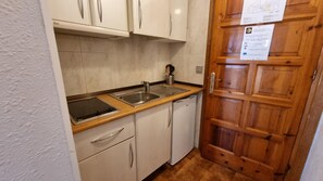 A compact kitchen with a sink, stove, and white cabinets.