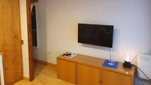 A room with a wooden cabinet, a mounted TV, and a desk with a lamp and papers. - 601 NEVADA 2 -estudi 2 pers- balco-Pas de la Casa -007647 (Pas de la Casa)