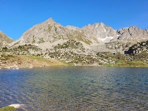 Ett bergigt landskap med klart vatten i förgrunden och bergiga berg i bakgrunden.