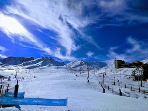 Pista de esquí nevada con telesillas y montañas al fondo.