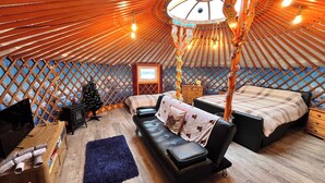 A yurt interior with a bed, sofa, and a small Christmas tree.