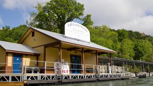 A waterfront building with a sign reading 'Fall Creek Marina' and a covered dock area. - 1 BR Walk in! No Cleaning Fees! Pools/hot tub! WAFFLES! Beach Pass! (Branson)