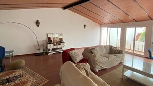A spacious living area with a high ceiling, a sofa, a red chair, a small table, and a decorative mirror. - Charming 5-Bed House in Granja (Granja)
