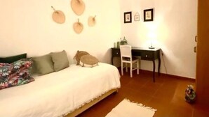 A bedroom with a bed, a desk, and a chair. There are wall decorations and a door. - Charming 5-Bed House in Granja (Granja)