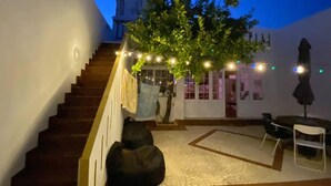 A staircase leading to a covered outdoor area with string lights, a tree, and a seating area with chairs. - Charming 5-Bed House in Granja (Granja)