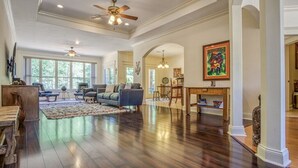 A spacious living room with dark hardwood floors, a large sofa, and a coffee table. There are two ceiling fans and a fireplace with a mantel. - Welcoming get-away in the Quiet, Gated Community of Hot Springs Village (Hot Springs Village)