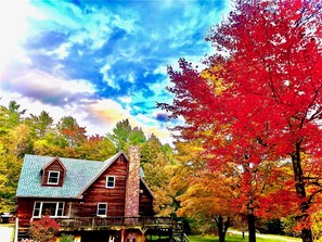 A wooden cabin with a stone chimney, surrounded by autumn foliage and a clear sky. - Catskills Windham Hunter Mountain Cabin Getaway (Maplecrest)