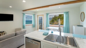 Cocina moderna con lavavajillas, lavabo y vista al océano.