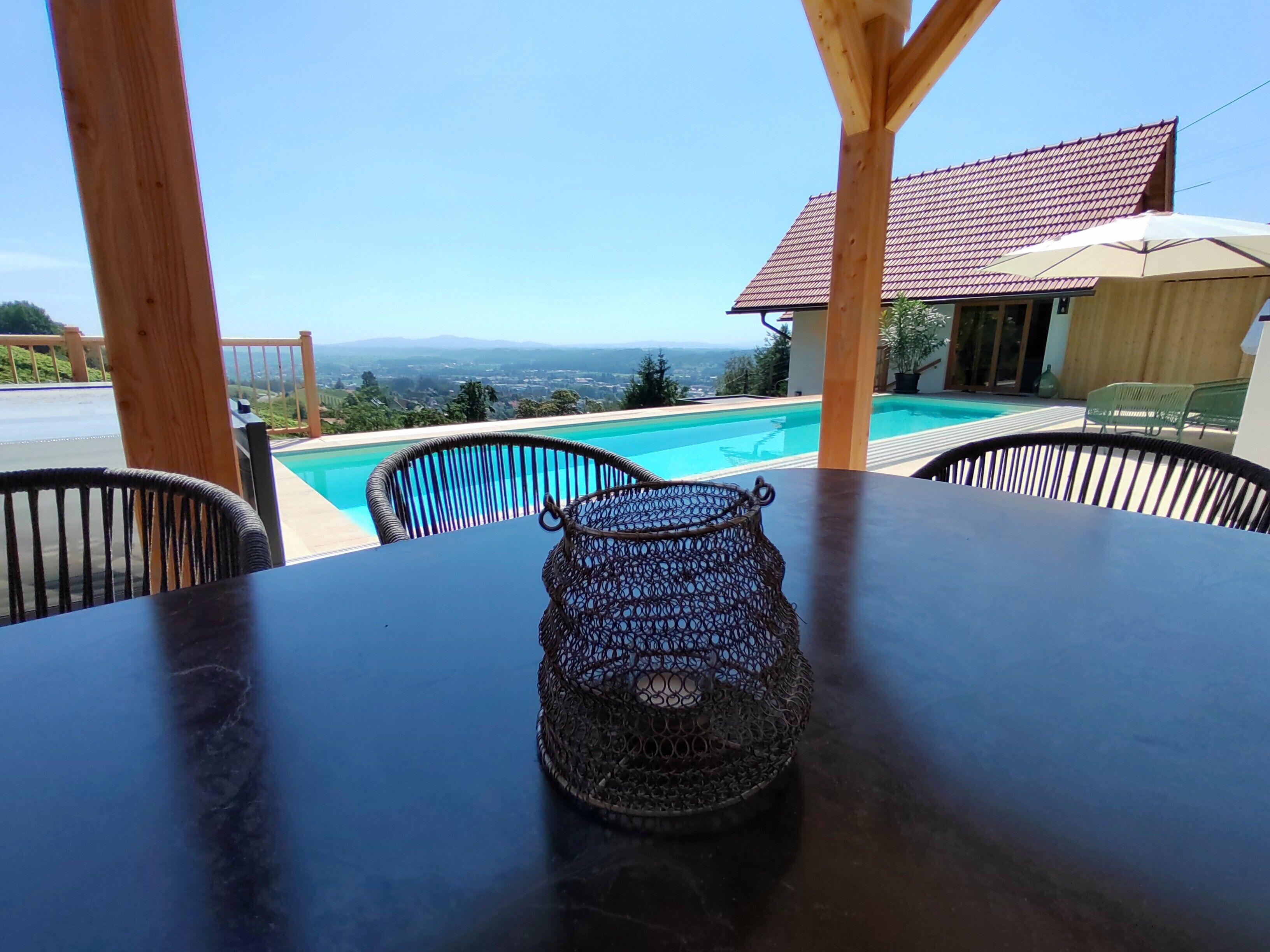 Une table avec un panier tressé, une piscine et une vue sur le paysage.