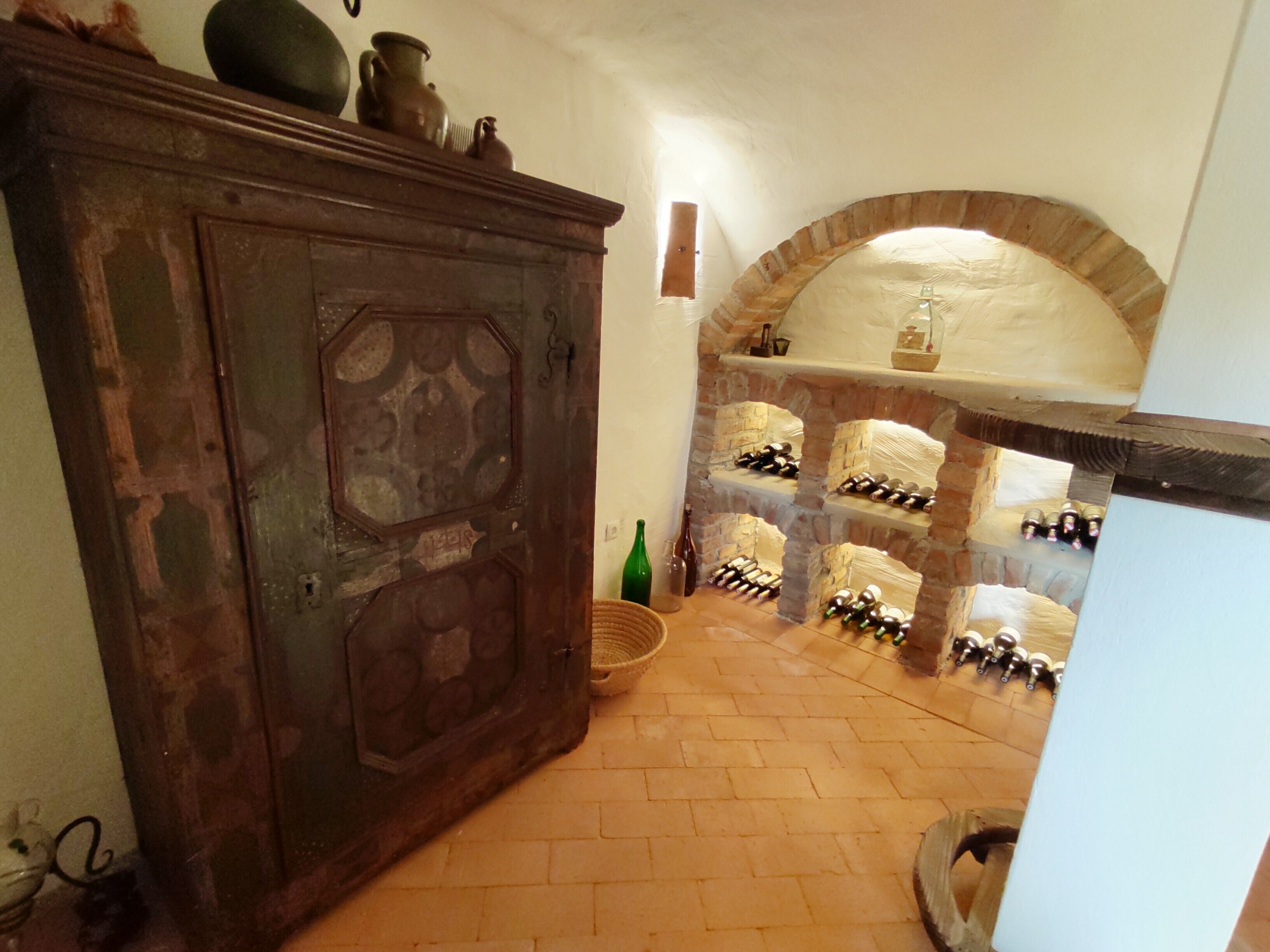 A room with a brick fireplace, a wooden cabinet, and a wine rack.