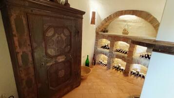 A room with a brick fireplace, a wooden cabinet, and a wine rack.