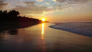 A beach at sunset with the sun low on the horizon, reflecting on the wet sand. - Rancho la Esmeralda  (Playa Sandiego)