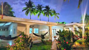 A modern hotel with a pool area, palm trees, and a hammock. - Rancho la Esmeralda  (Playa Sandiego)