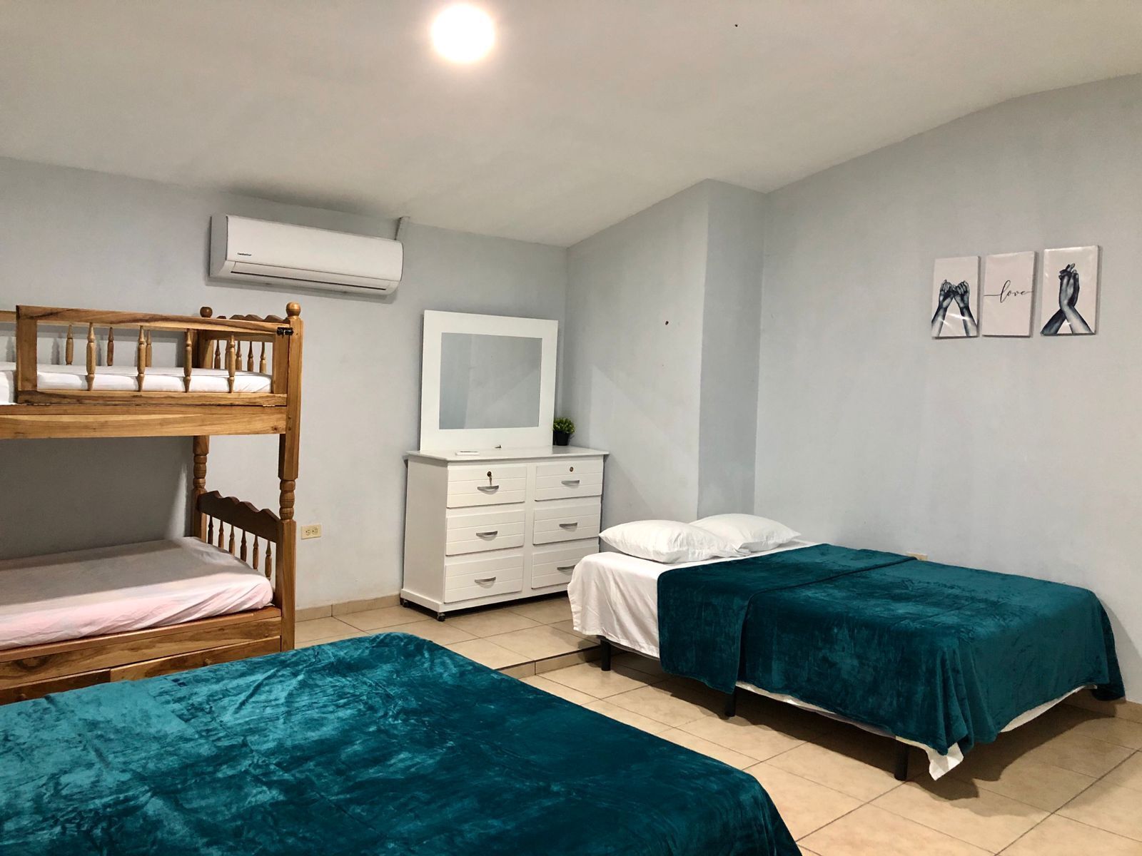 Ein Zimmer mit Etagenbetten, einem weißen Schminktisch, einem Spiegel und drei gerahmten Bildern an der Wand.