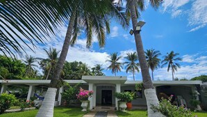A building with a white facade, a central entrance, and palm trees in the background. - Rancho la Esmeralda  (Playa Sandiego)