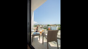 Relax on the balcony with a wicker chair and table, taking in the views of the surrounding urban landscape and distant coastline.