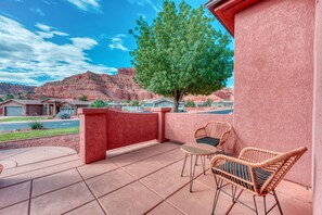 A patio with two wicker chairs, a red wall, and a view of red rock formations.