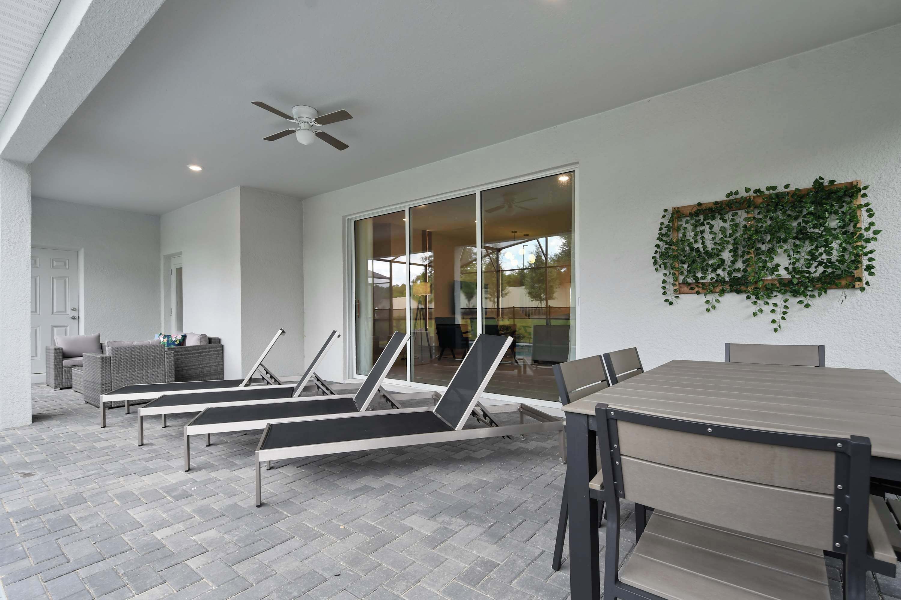 Un patio con sillones de descanso, una mesa y un ventilador de techo.