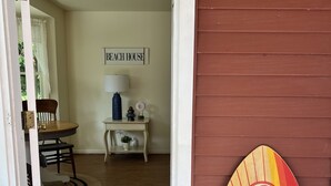 Ein Strandhaus-Interieur mit einem Schild mit der Aufschrift 'Beach House', einem Surfbrett und einem Holzboden.