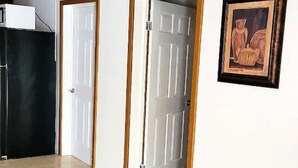 Ein Flur mit Deckenventilator, zwei weißen Türen, einem gerahmten Bild an der Wand und einem gefliesten Boden.