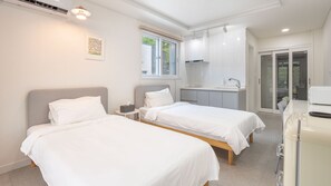 A modern hotel room with two beds, a kitchenette, and a sliding glass door to the outside. - Hongcheon Toliaigeullaemping (Hongcheon)