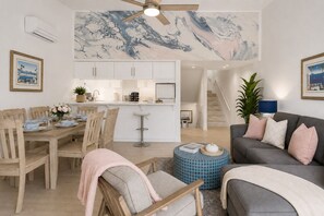 Ein modernes Wohnzimmer mit Essbereich, einer Küche und einer Treppe.