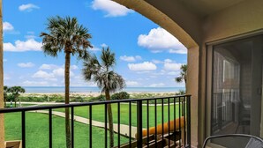 A balcony with a view of a golf course, palm trees, and the ocean. - 2nd-Floor Turtle Dunes Unit with Breathtaking Views (Fernandina Beach)