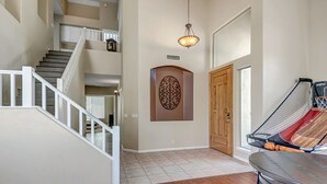Um corredor amplo com escada, um detalhe decorativo na parede e um cesto de basquete.