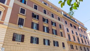 A multi-story building with a beige facade and dark shutters on the windows. - Santamaura Vatican Apartment - 50 meters from the Vatican walls! (Roma)