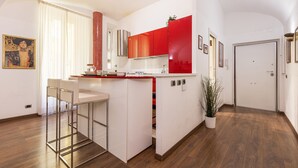 A modern kitchen with a central island, white cabinets, and red accents. - Santamaura Vatican Apartment - 50 meters from the Vatican walls! (Roma)