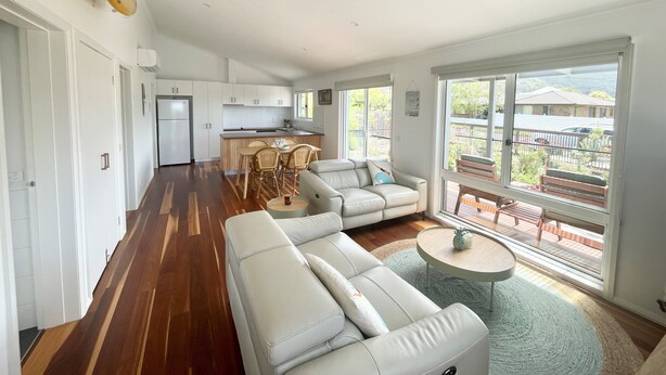 A spacious living area with a sofa, a dining table, and a kitchen in the background.