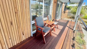 A wooden deck with a glass door leading to a patio area.
