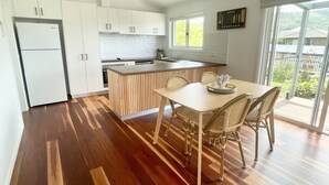 A modern kitchen with white cabinets, a wooden island, and a dining area with wicker chairs.