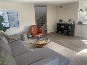 Un salon moderne avec une table basse en verre, un fauteuil en cuir et une bibliothèque.