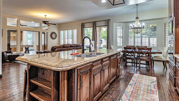 A spacious kitchen with a large island, wooden cabinets, and a chandelier. - Private Pool, Pool Table, BBQ, Near San Diego Padres & Seattle Mariners Spring Training + FREE GOLF! (Glendale)