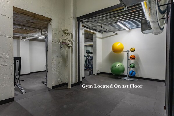 A gym on the first floor with exercise equipment and a wall-mounted ball rack.