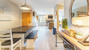 Una cocina moderna con encimera de madera, una mesa de comedor con sillas y una lámpara colgante.