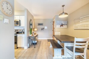 Una cocina moderna con armarios blancos, encimera de madera y una zona de comedor con banco y sillas.