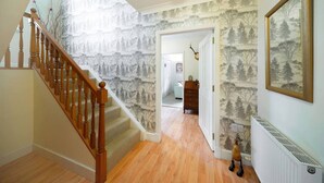 A staircase with wooden balusters leading to a landing with a radiator and a framed picture on the wall. - Earnside Cottage, Tranquil Escape in Comrie (Comrie)